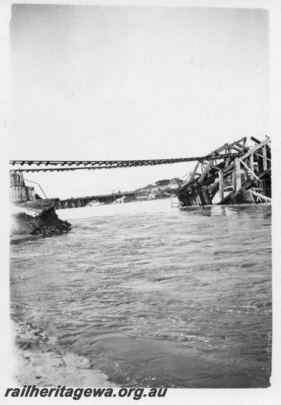 P01802
Fremantle Railway Bridge collapse which occurred on the afternoon of the 22nd of July, 1926, North Fremantle, due to the 1926 flood, shows rails suspended and the collapsed trusses.
