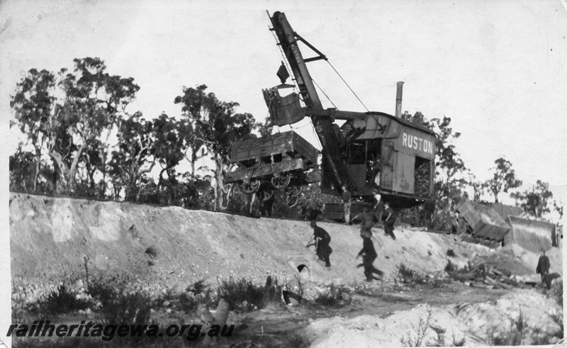P02009
7 of 14. Ruston steam shovel righting derailed side tipping wagons on embankment, view of wagon suspended from shovel bucket, front and side view, construction of Denmark-Nornalup railway, D line.
