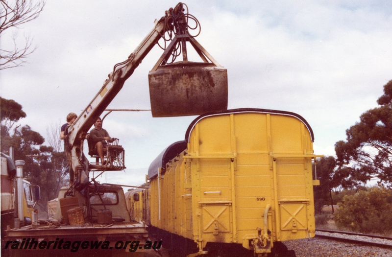 P03584
RCK class 23966, ex RCA class, with extended sides and ends with a corrugated iron sliding roof, fertilizer being unloaded by truck mounted bucket crane, end view, Moora, MR line
