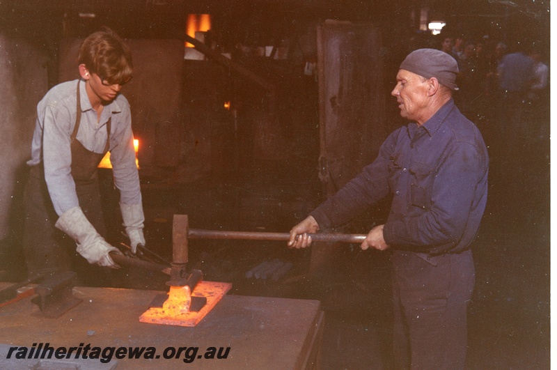 P04018
3 of 4 images taken in the Blacksmith Shop, Block 2,  Midland Workshops,  apprentice on the left and a tradesman forging a  red hot piece of metal with a hand held hammer

