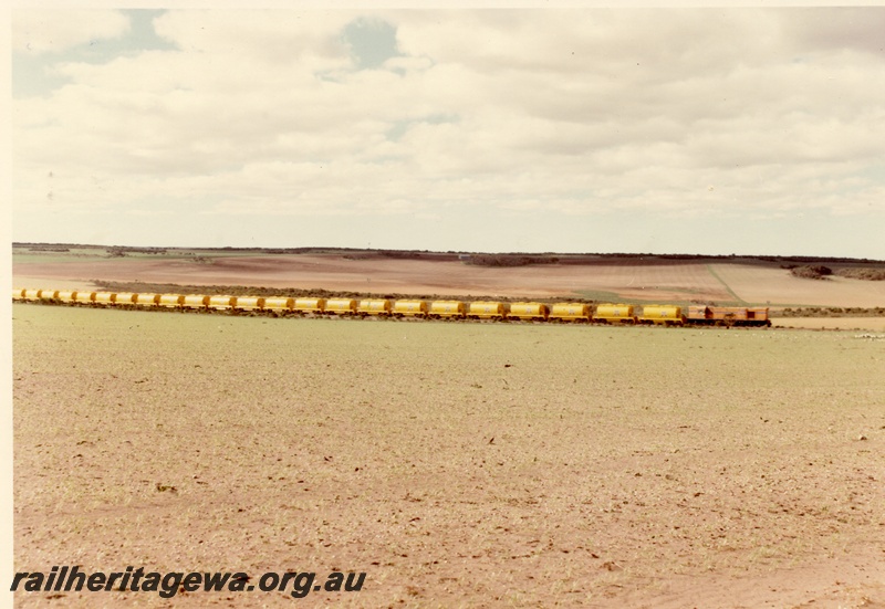 P04025
Diesel loco, Westrail orange with blue stripe, heading mineral sands train of at least 23 wagons, side view from long distance, DE line
