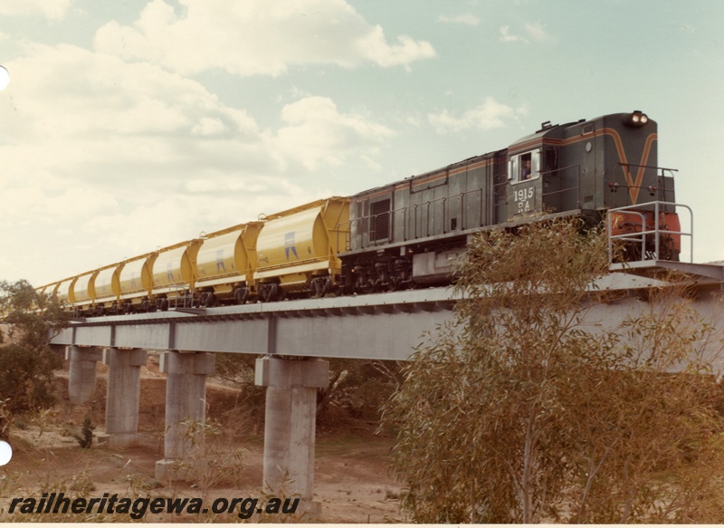 P04028
2 of 2 images, RA class 1915, green with red and yellow stripe, hauling train of XE class mineral sand wagons, crossing steel and concrete bridge, Irwin River. DE line

