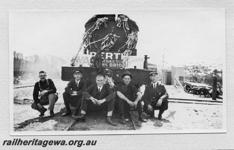 P09353
Front view of the loco on the first train Norseman through to Salmon Gums, Salmon Gums, CE line, crew posing in front of the loco. Decorations and signs on the smokebox
