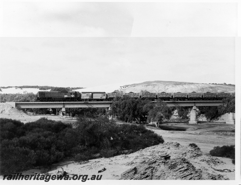 P10477
AB class 1536 diesel locomotive hauling 28 QW class container wagons on the Irwin River bridge on the Eneabba railway. The bridge is of concrete construction and the wagons were former W class steam locomotive tender chassis. DE line.
