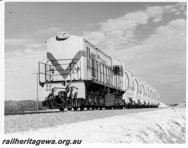P10538
RA Class 1908 diesel locomotive, Westrail orange with blue and white stripe, with a short rake of XE Class ilmenite hopper wagons between Dongara and Eneabba. Front and side view of locomotive. DE line.
