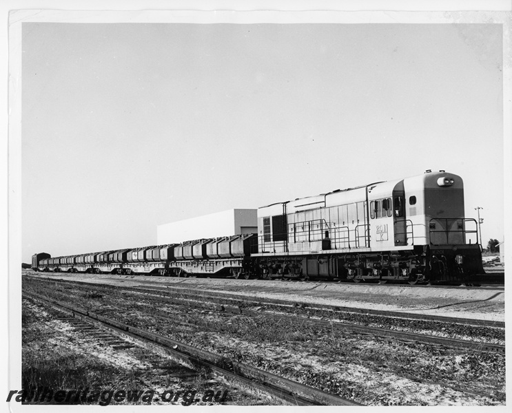 P10749
K class 201 standard gauge diesel locomotive at the head of a rake of WF class 30011 standard gauge flat top wagons loaded with nickel containers at possibly at Esperance.
