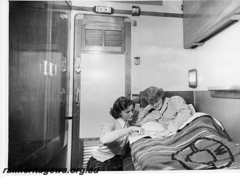 P10757
AH class narrow gauge first class sleeping car compartment showing the lower bunk made up. The upper bunk is visible above the passengers shoulder. 
