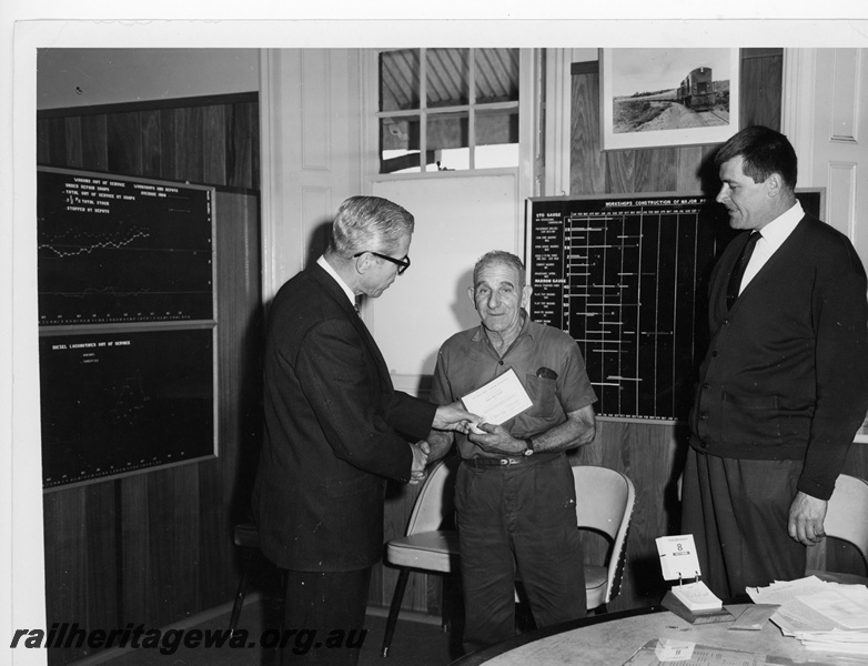 P10945
Midland Workshops Furnaceman, Mr C Burnett, being presented with the 'Wise Owl Club' safety award by the Chief Mechanical Engineer, Mr W C Blackeney-Britter with safety officer Maurice Tomlin looking on.
