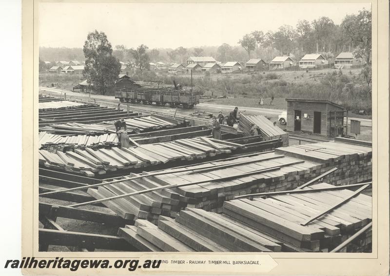 P12051
WAGR timber mill at Banksiadale, workers loading timber into a wagon, loaded wagons in the yard, townsite and worker's houses in the background. (scanned print located in MC1B2G)
