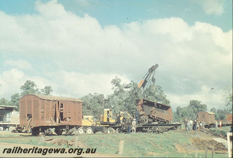 P12223
Damaged FD class van, wreckage of a R class bogie open wagon being lifted onto a black livered QU class flat wagon by a road crane, Gingin accident. MR line.
