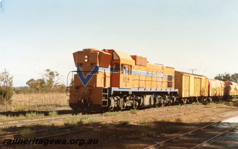 P14711
A class 1514 diesel locomotive in Westrail orange livery, front and side view, on goods train, Narrikup, GSR line.
