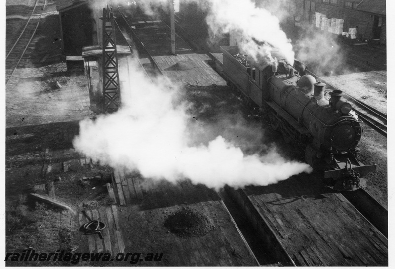 P15123
ESL class 328 steam locomotive at Katanning Loco depot. Overhead view from coal stage showing ash pits in foreground and portion of shed in background. GSR line.
