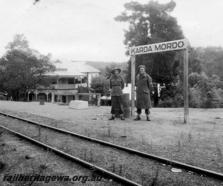 P15146
Karda Mordo station nameboard with servicemen standing next to the sign. MW line. Mundaring Weir Hotel in background.
