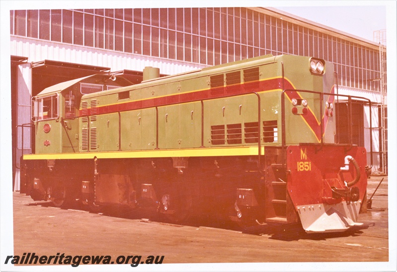 P15945
M class 1851, in green with red and yellow stripe, standing outside shed, side and end view, long end to camera
