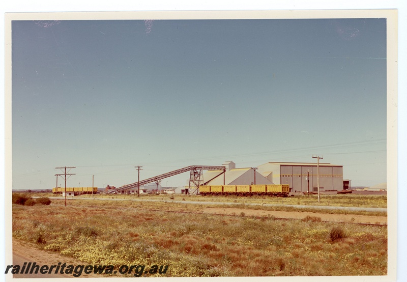 P15954
One rake of six QW class wagons, another rake of eight QW class wagons and van, unloading mineral sands, conveyor belt, storage sheds, water pipeline, distant view
