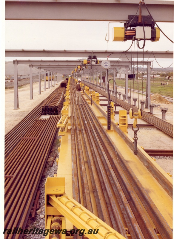 P15992
Loading rails after flash butt welding, worker, overhead winches, view along the length of the rails
