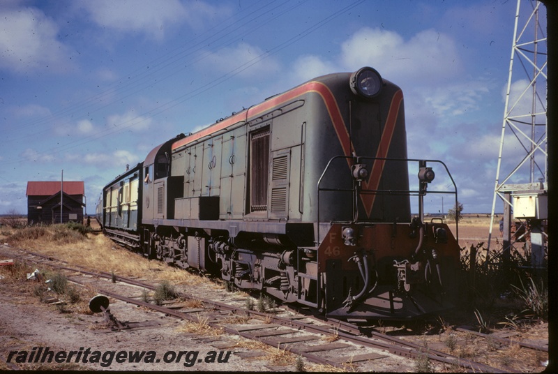 P16678
F Class 46 in green with red and yellow stripe, on passenger train, Busselton, station building, point lever, aerial tower, side and front view
