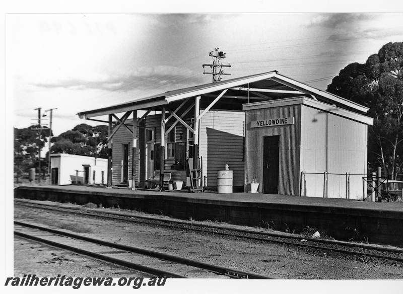 P16699
Station building under an overall canopy roof, Out of Sheds on the platform, another shed at the end of the platform, nameboard,  seat, baggage trolley, Yellowdine, EGR line, view along the platform.
