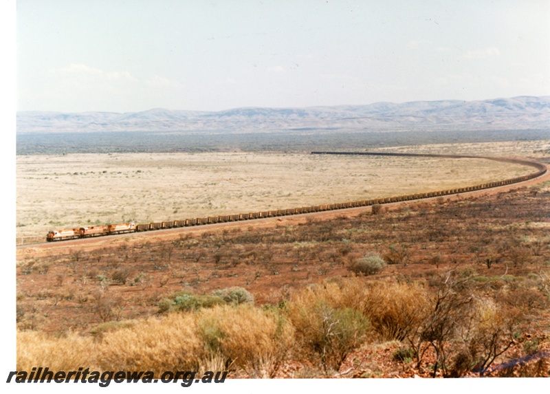 P16764
Mount Newman (MNM) triple headed 180 car loaded ore train at 227 km near Garden loop. Distant view. 
