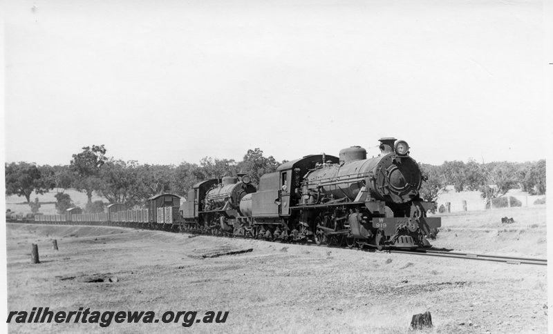 P17375
W class 919, W class 914 steam locomotives at the head of 54 Goods between Wagin and Collie, near Cordering, WB line, front & side view of front locomotive. Both locomotives have water tankers behind their tenders. 
