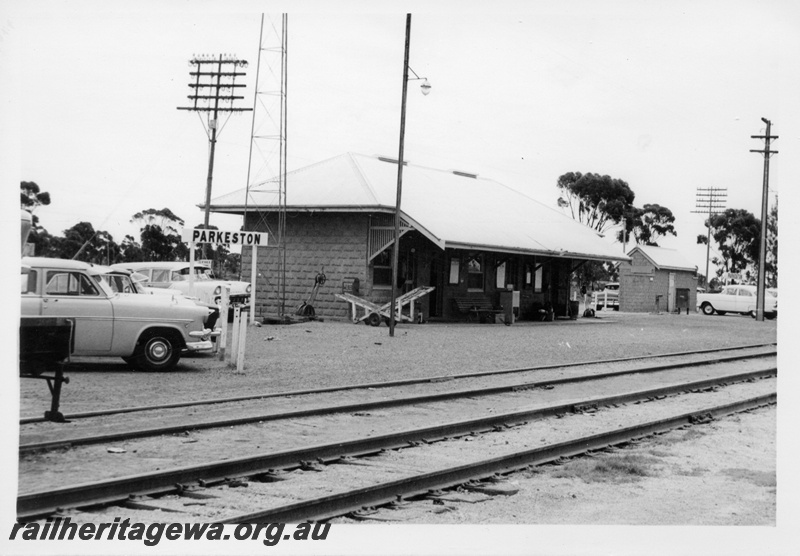 P17552
Station building, trackside shed, hand luggage trolley, cars parked, station nameboard, Parkeston, TAR line, c1968 
