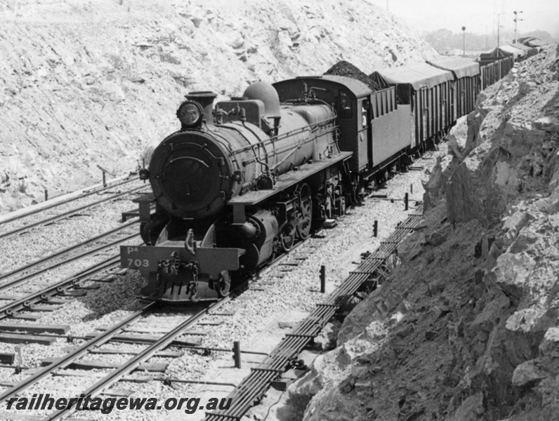P17733
PM class 703 steam locomotive  with a PR class dome working No. 105 goods train for Merredin. The train is departing through East Avon and of note is the signalling wiring and rodding for the points. Semaphore and automatic signals in the background.
