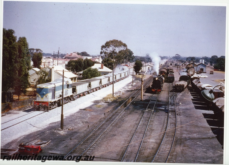 P20052
An unidentified H class standard gauge diesel locomotive with a ballast train near the Kellerberrin Station. An unidentified V class steam locomotive waits with its train on the narrow gauge loop while an unidentified PM class steam locomotive shunts the goods shed road. The headlight of an approaching eastbound train is seen in the background. EGR line
