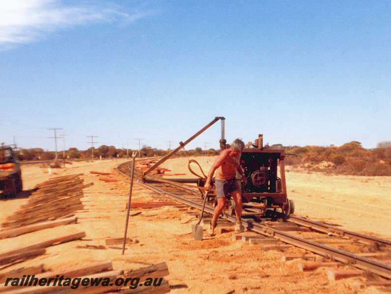 P20544
Track work, worker with shovel, trackwork machinery, sleepers, motor vehicle, view from trackside
