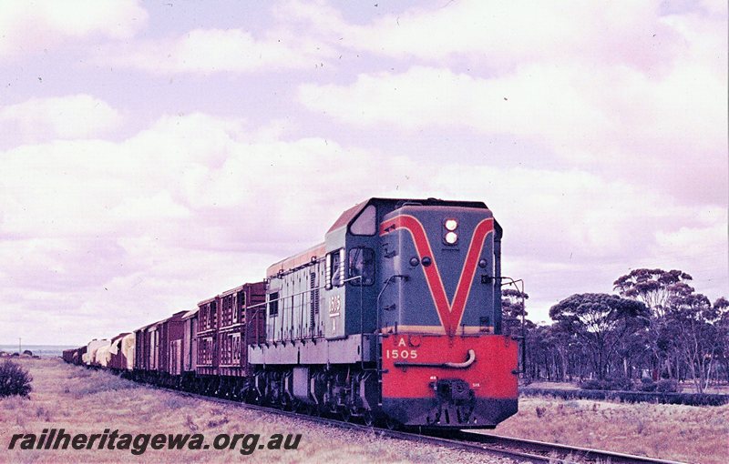 P20762
A class 1505 (green with red/yellow stripe livery) number 98 goods between Hines Hill and Doodlakine. Goldfields Water Pipeline  to the right of the train. EGR line. 
