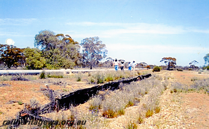 P20841
Railway platform, abandoned and derelict, pipeline in the background, view along the platform, Bob Johnston, Lyle Metcalf, Peter Proudfoot, Mick Stathy walking along the platform, Yellowdine, ER line
