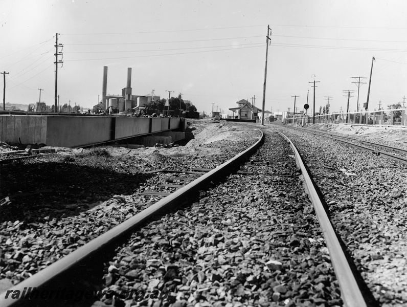 P20934
Track, steel girder with concrete pylons rail bridge over Great Eastern Highway, signal box and station buildings in distance, signal, industrial buildings, Rivervale, SW line, view along tracks towards station. See P20928.
