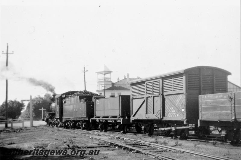 P21410
Midland Railway Co of Western Australia (MRWA) C class 18 on goods train including van and wagons, waiting to cross Great Eastern Highway, crossing, Midland, MR line, view looking along the side of the train from the rear towards the highway
