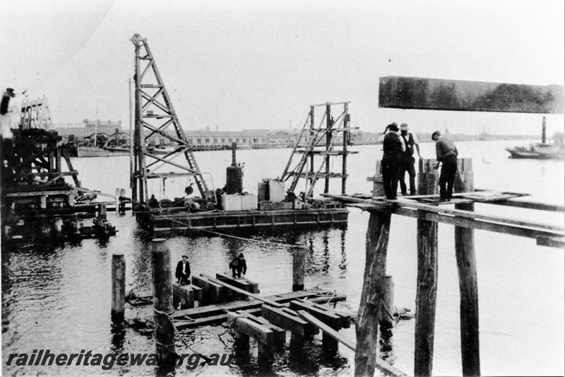 P21472
Timber trestle rail bridge over Swan River, being rebuilt after  the Fremantle Railway Bridge collapse which occurred on the afternoon of the 22nd of July, 1926, floating derrick, workers, Fremantle, ER line, view from North Fremantle bank 
