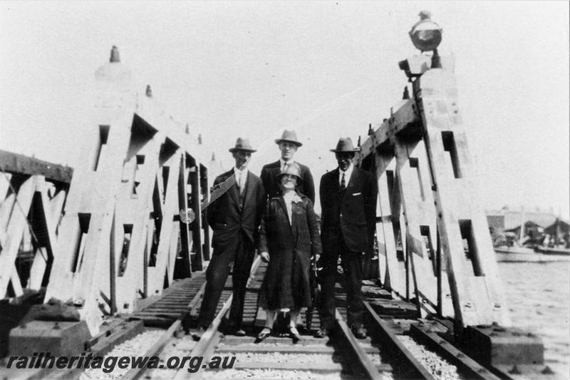 P21473
Timber  trestle rail bridge over Swan River, reopening after rebuilding after the  Fremantle Railway Bridge collapse which occurred on the afternoon of the 22nd of July, WAGR Ways & Works Superintendent Charles Hoare (rear right) with three other persons, standing on the tracks at the end of the rebuilt bridge, ER line, track level view

