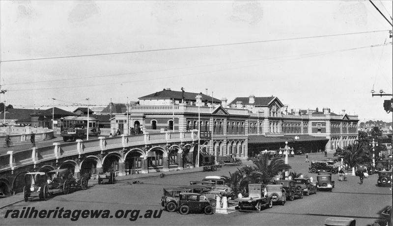 P21483
Perth Station, streetside view looking east from the Horseshoe Bridge, horse drawn vehicles and motor vehicles in the forecourt, tram on the Horseshoe Bridge
