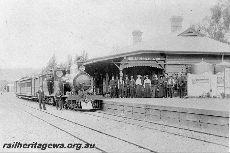 P21524
O class loco on mixed train, standing at station, station building, platform, canopy, mixed group of people on platform, crew, tracks, picket fence, water tanks, unofficial opening of the station, Bridgetown, PP line, 
