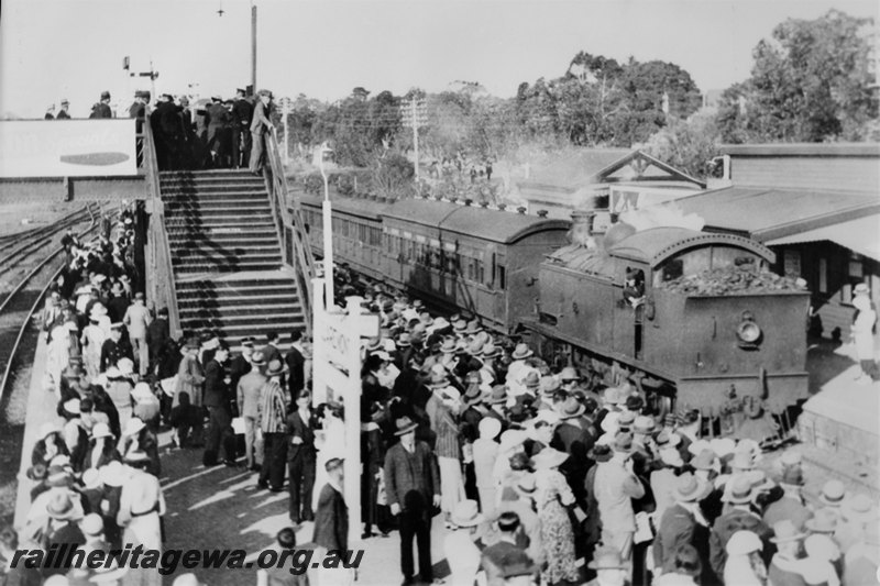 P22583
D class loco on passenger train, station buildings, platforms, nameboard,  overhead pedestrian footbridge, crowds on platforms and footbridge,  Showgrounds Station, ER line, view from elevated position, c1935
