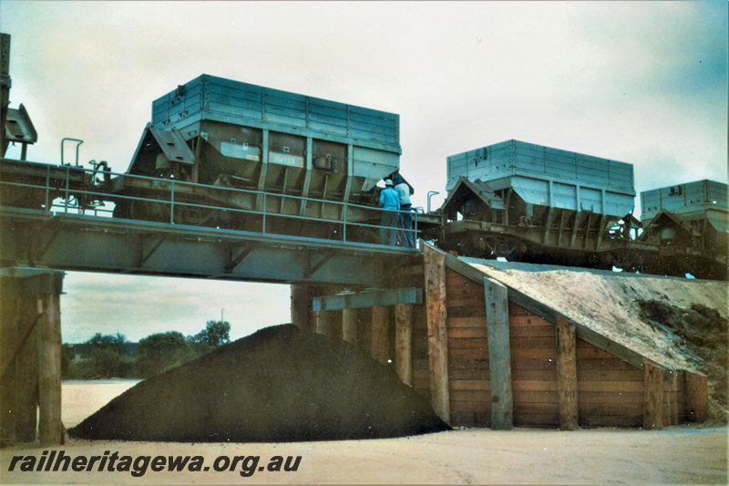 P22862
WMD class 57 hopper wagon, WMD class 39 hopper wagon, in train discharging load from overpass to ground below, workers, end and side view from ground below track level
