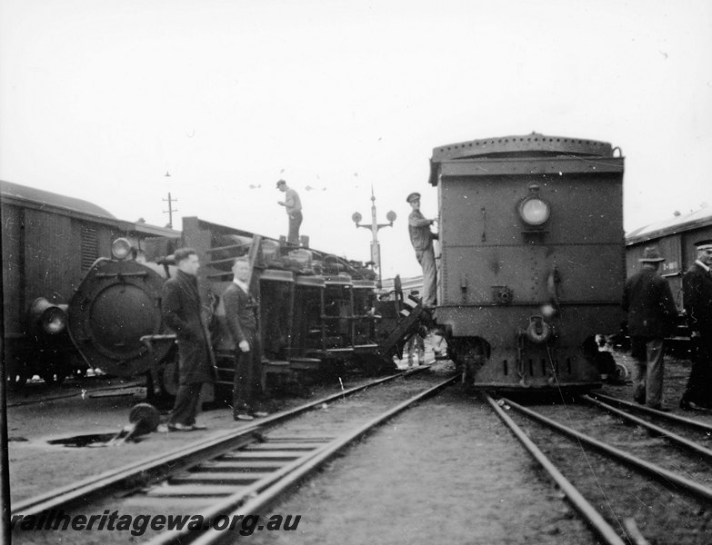 P22923
Derailment of steam locomotive 2 of 3, loco on its side off track, another loco tender to camera, workers, tracks, signals, view of front of derailed loco 
