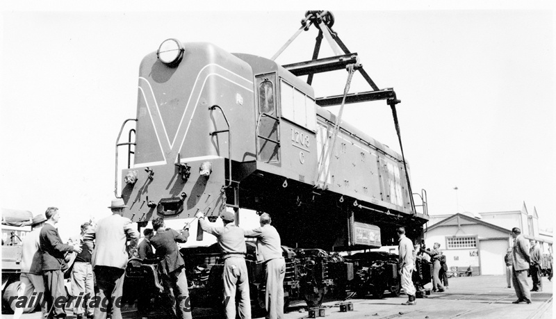 P23083
C class 1703, body being lowered onto wheels by port crane, warehouse, tracks,  onlookers, workers, Fremantle, ER line, end and side view from wharf
