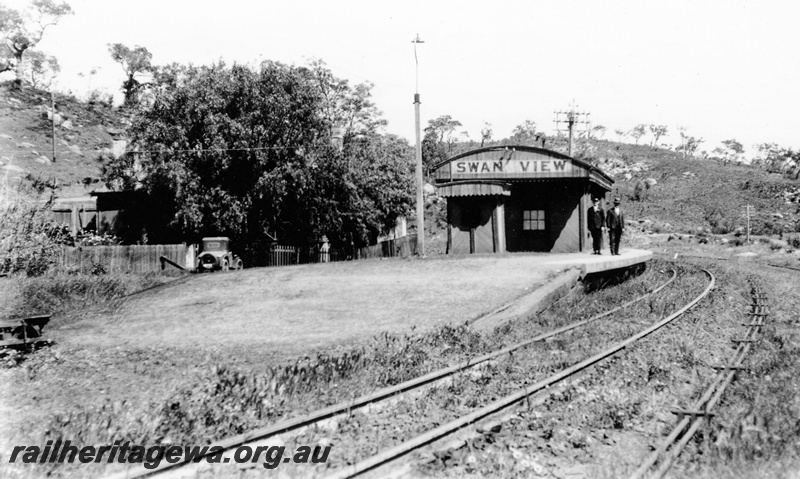 P23116
Station building, platform, platform light, point rodding, two men standing on the platform,  track, Swan View, ER line, view from track level looking west.
