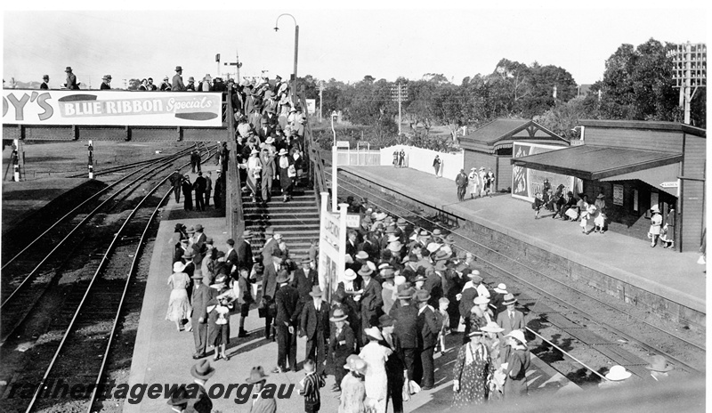 P23141
Crowded platforms and footbridge, station buildings, station nameboard, signal, tracks, Claremont, ER line, elevated view, waiting for a  Royal Show train.
