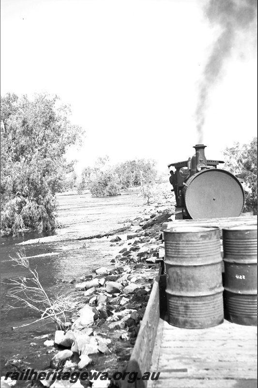 P23162
1 of 3 views of the Port Hedland floods, PM line , H class 8802  wagon with drums being hauled by a G class loco, view along the train. 
