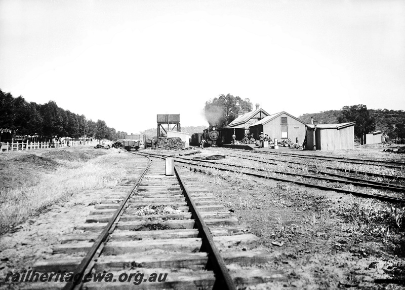 P23265
Station building, water tower with cast iron tank, steam locomotive hauled train in station. Army personell on the platform, Mingenew,  MR line., view looking along the track
