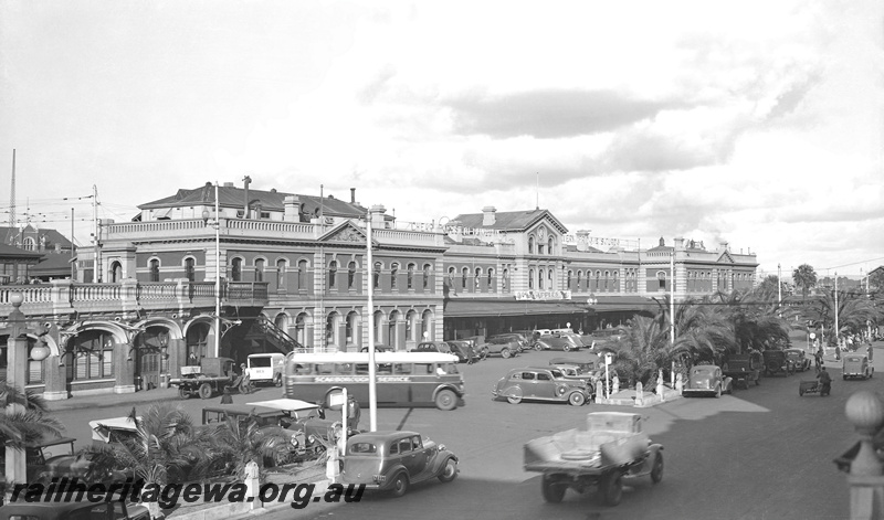 P23266
Perth Railway station forecourt with parked cars,  Wellington Street with traffic, looking east. Scarborough Bus Service bus in foreground. ER line. Same as P07701
