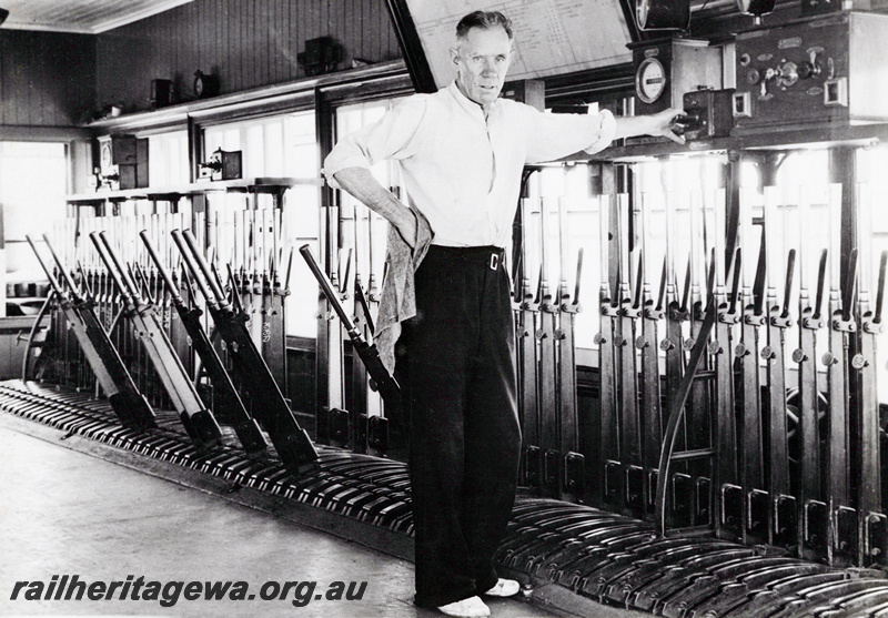 P23611
Interior view of signal box, Mr E. Flynne standing in front of the levers, East Perth, ER line
