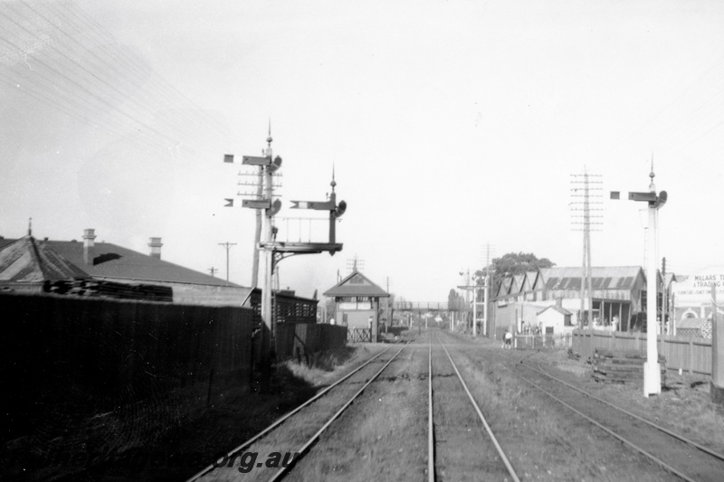P23771
Bracket signal. Level crossing with crossing gates, signal box, Millars Timber and Trading Co. building on the right hand side, , East Perth, view along the track looking east

