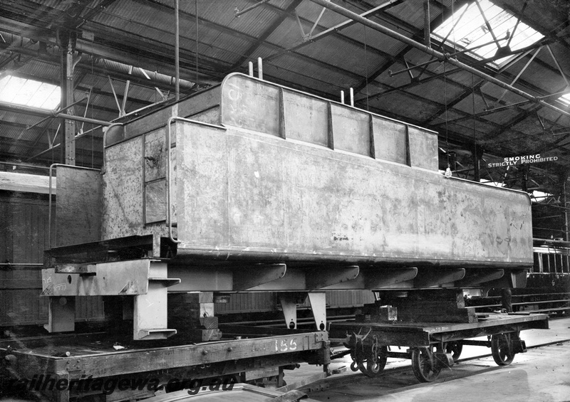 P23859
S class loco tender, ready for painting, supported on wooden blocks over two four wheel wagons 155 and JETTY 307, Midland workshops, Midland, ER line, front and side view
