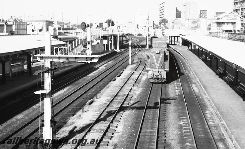 P23948
RA class 1918, on goods train, bracket signals, platforms, canopies, ramp, road bridge, city buildings, Perth station, ER line, front view from elevated position
