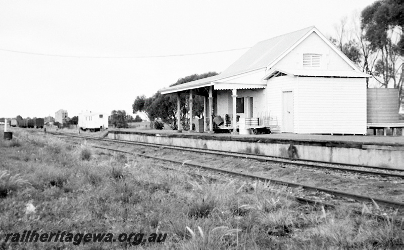 P23962
Station building, platform, trolleys, water tank, tracks, van, Dongara, MR line, view from track level 
